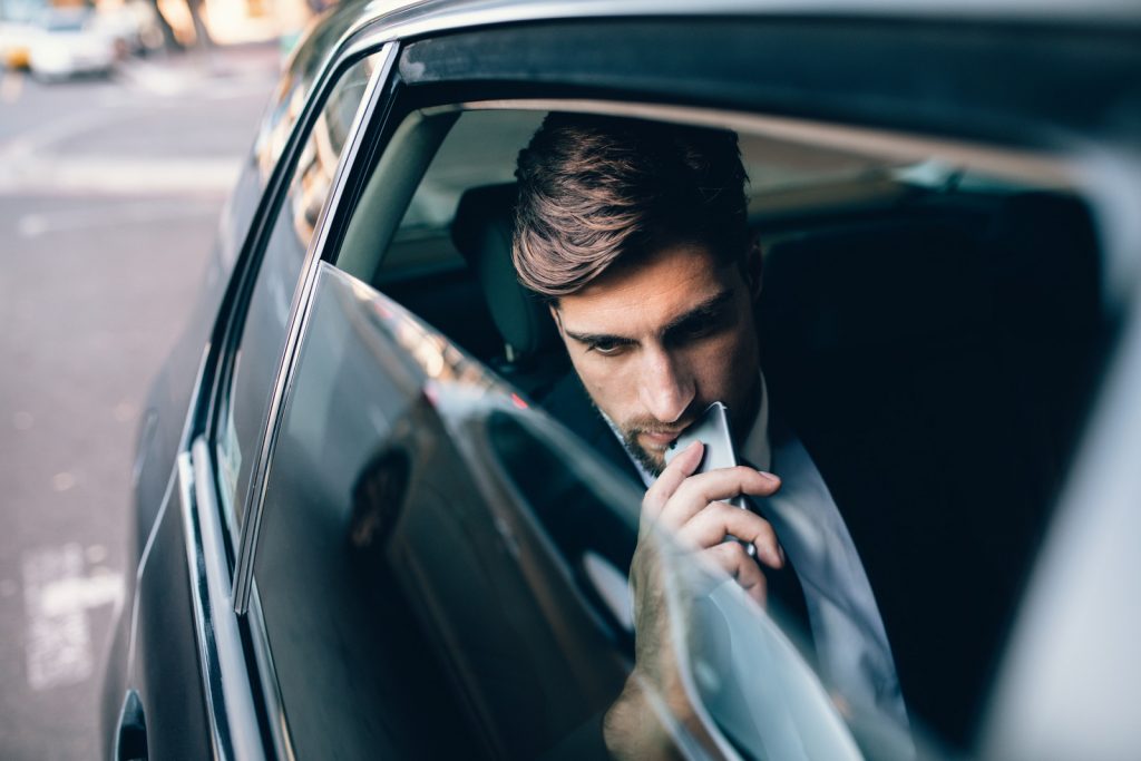 phone and thinking. Caucasian male business executive travelling by a cab.